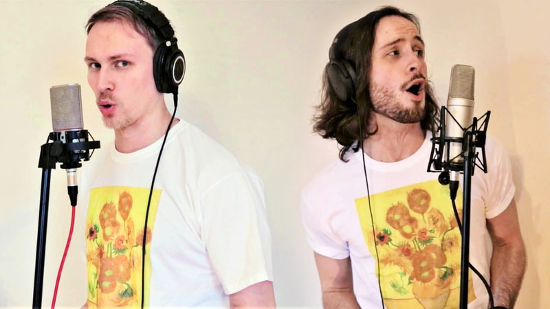 Two men wear white t-shirt with prints of Van Gogh's Sunflowers on the chests. They stand at mic stands and sing. One is fair-haired, short-haired and bearded; the other is dark-haired, long-haired and bearded. 